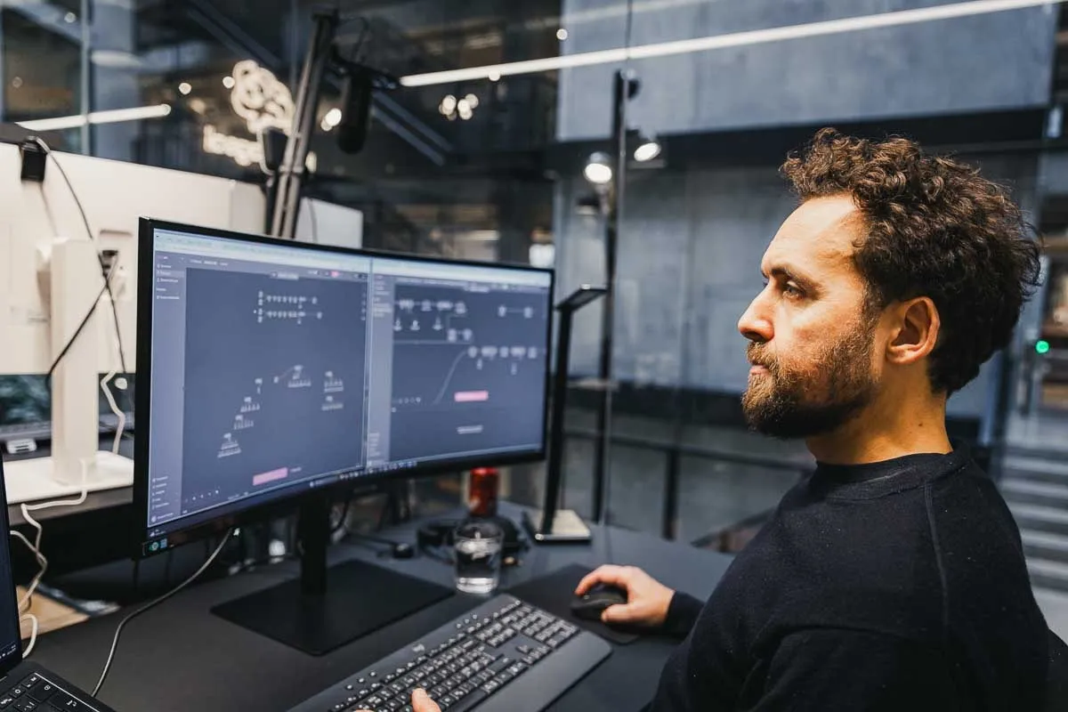 A person works at a large monitor showing a workflow of connected steps.